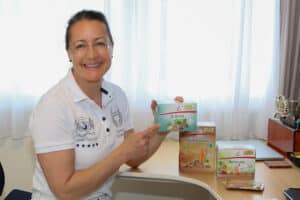 Petra in ihrer Vitalpraxis hält ein Produkt in der Hand, welches die Leber im Speziellen unterstützt.