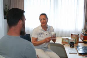 Petra erklärt einem Klienten, wofür welche Mikro- und Makronährstoffe eingesetzt werden.