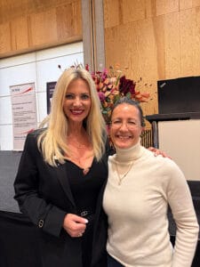 Petra Büeler steht mit Veronika Renz vor der Bühne beim SVNM Jahresmeeting. 