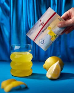 Gelbes Mineraliengetränk im gewellten Glas vor blauem Hintergrund