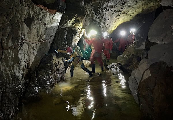 Petra führt eine Gruppe Menschen in der Höhle sicher durch ein trübes Gewässer