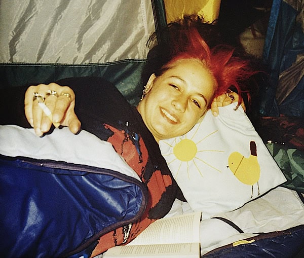 Petra als Jugendlliche im Grufti-Gothik- look. In einem Zelt liegend und in die Kamera lächelnd mit Zigarette in der Hand und sehr happa an diesem Open-Air sein zu können.