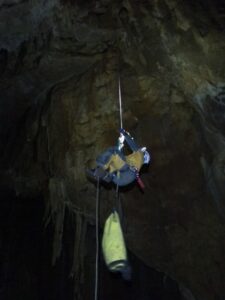 Person steigt in der Höhle an einem Seil hoch