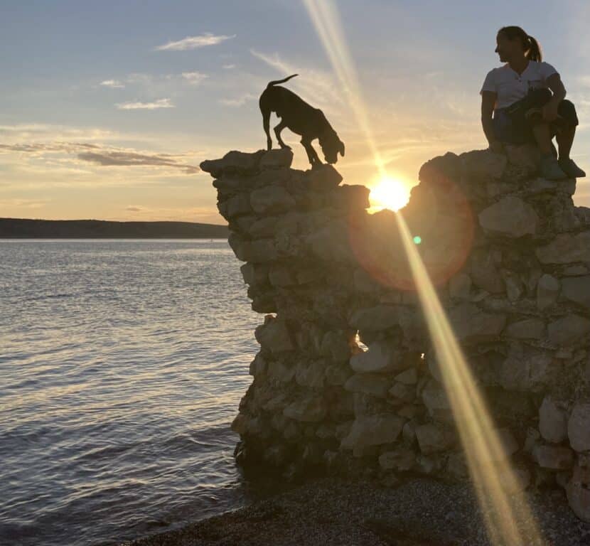 Hund und Frauchen auf Ruinenstück am Klettern während des Sonnenuntergangs