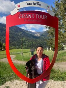 Petra mit schwarzem Hund Amor im Bilderrahmen mit Sicht auf die Schweizer Klippe Creux du Van